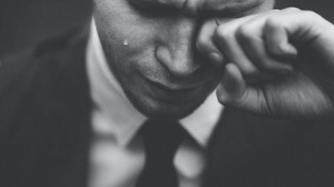 Closeup of man crying and rubbing his eye.